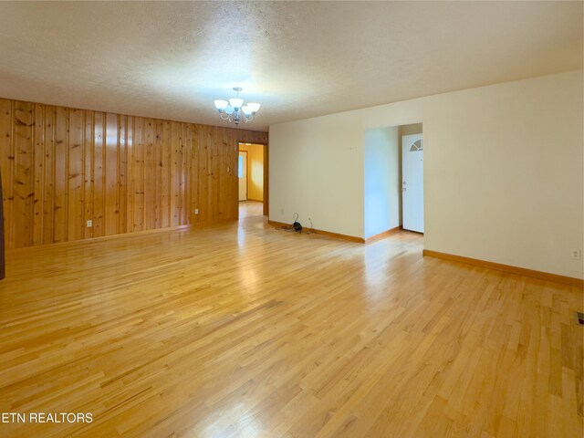 161 Cedar Ln, Rocky Top, TN 37769 - unfurnished room featuring light wood-type flooring, a chandelier, baseboards, wooden walls, and a textured ceiling