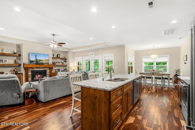 kitchen featuring a sink, dishwasher, brown cabinetry, a breakfast bar, and dark wood finished floors