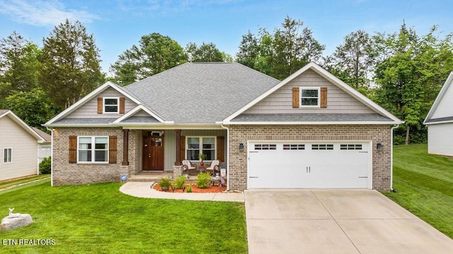 craftsman house with brick siding, a front yard, driveway, covered porch, and an attached garage