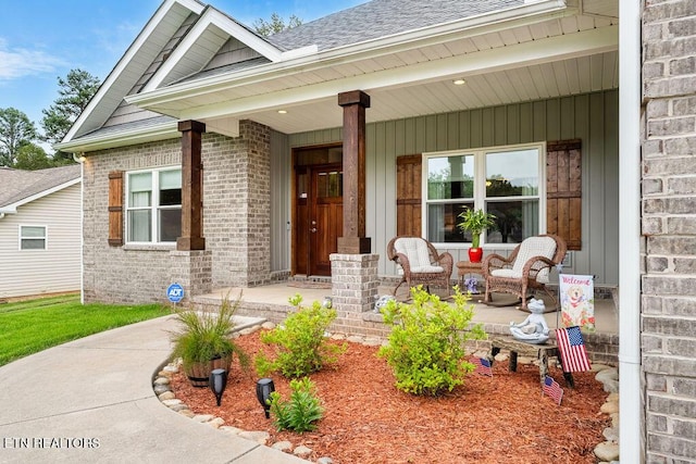 property entrance featuring a porch, brick siding, and roof with shingles