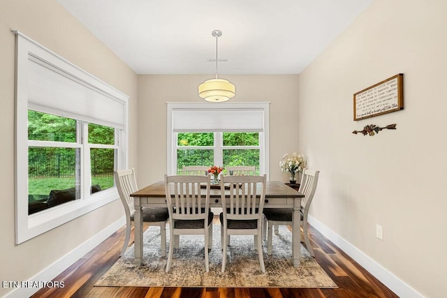 dining room featuring plenty of natural light, baseboards, and dark wood-style flooring