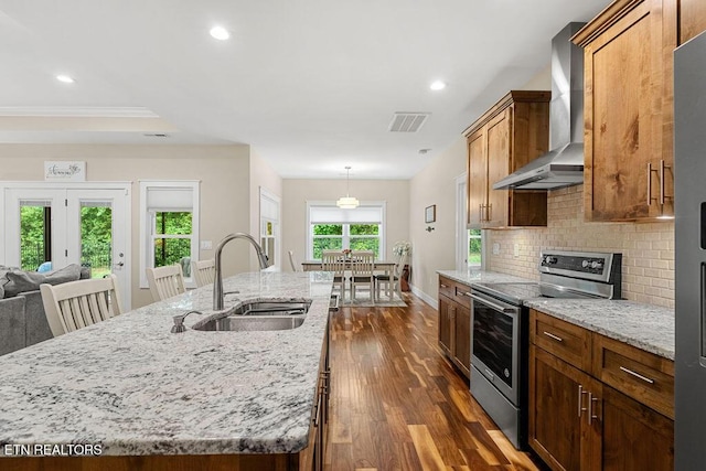 kitchen with stainless steel electric range oven, a sink, wall chimney exhaust hood, dark wood finished floors, and decorative backsplash