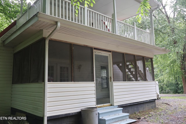view of property exterior featuring a sunroom, a balcony, and entry steps