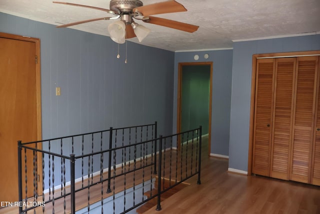 hallway featuring an upstairs landing, wood finished floors, a textured ceiling, and baseboards