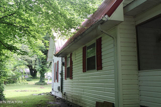 view of property exterior with a yard and metal roof