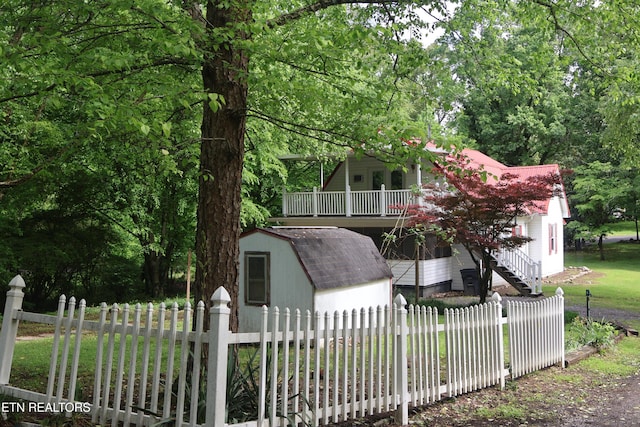 view of front of house featuring a shed, an outbuilding, a fenced front yard, stairs, and a wooden deck