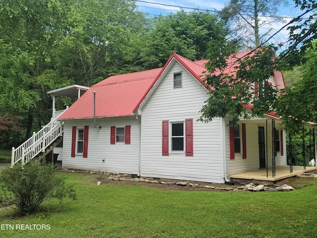 rear view of property with a porch, stairway, a yard, and metal roof