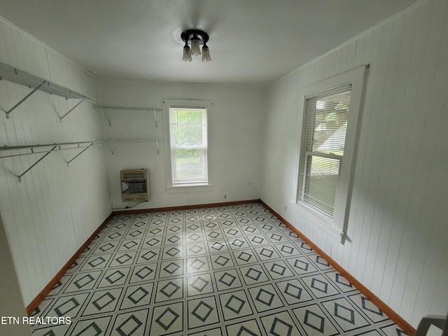 laundry room featuring heating unit, wooden walls, and baseboards