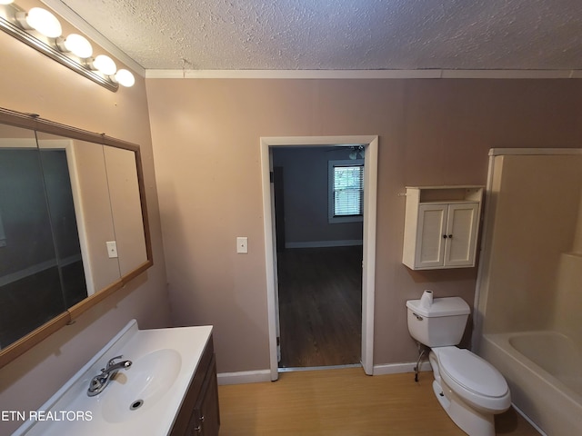 full bath with wood finished floors, a textured ceiling, toilet, vanity, and baseboards