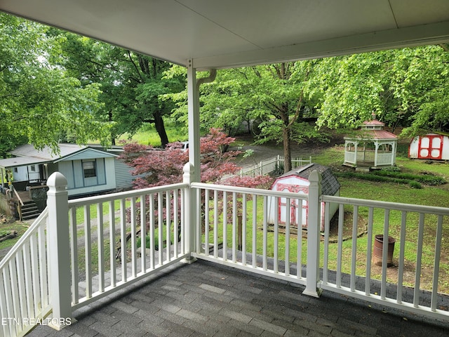wooden deck featuring a storage shed, an outbuilding, and a lawn