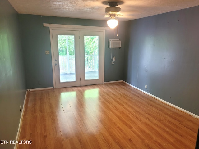 unfurnished room with a ceiling fan, light wood finished floors, baseboards, a textured ceiling, and a wall unit AC