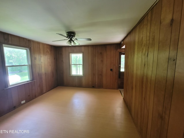 unfurnished room with wooden walls and ceiling fan