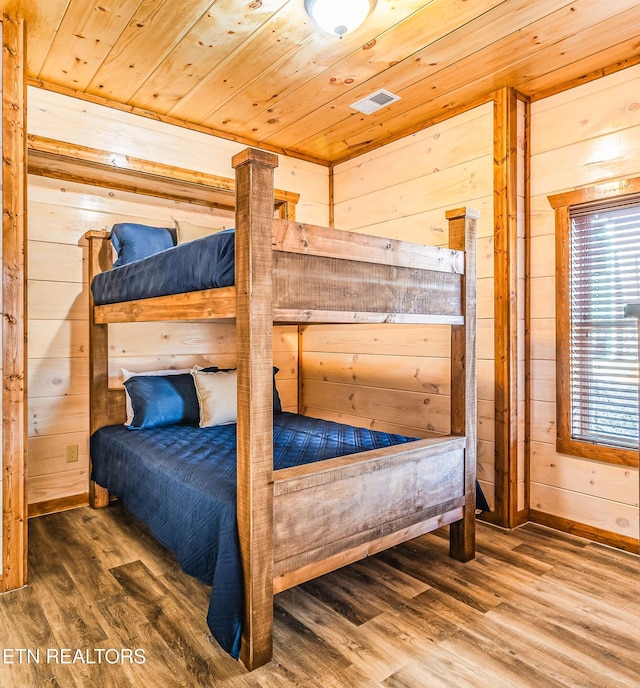 bedroom with wood ceiling, wooden walls, wood finished floors, and baseboards