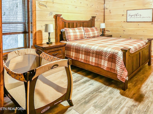 bedroom with wood finished floors and wood walls