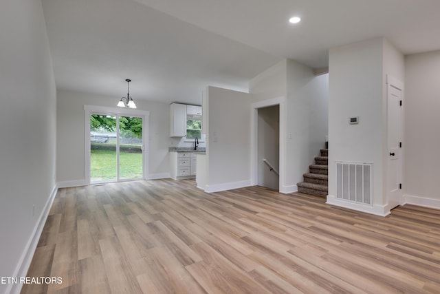 7513 Inverrary Cir, Knoxville, TN 37918 - unfurnished living room featuring light wood-style flooring, a sink, stairs, a chandelier, and baseboards