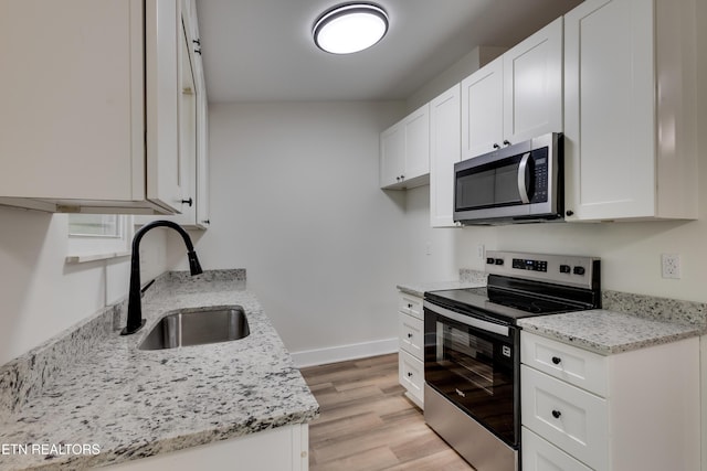 7513 Inverrary Cir, Knoxville, TN 37918 - kitchen featuring appliances with stainless steel finishes, a sink, white cabinetry, light stone counters, and light wood finished floors