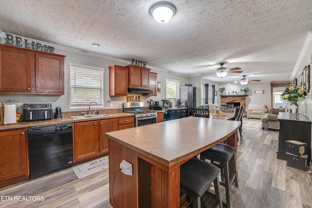 1418 Gulley River Rd, Harrogate, TN 37752 - kitchen featuring stainless steel gas stove, black dishwasher, a sink, a fireplace, and under cabinet range hood