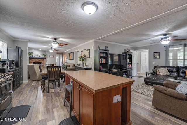1418 Gulley River Rd, Harrogate, TN 37752 - kitchen featuring open floor plan, ceiling fan, a center island, a textured ceiling, and brown cabinetry