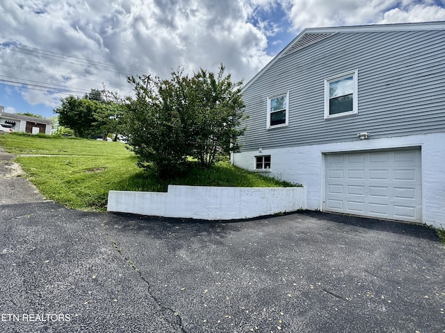 view of side of property with an attached garage, a yard, and asphalt driveway