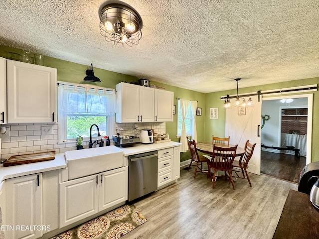 kitchen featuring dishwasher, a sink, white cabinetry, and a textured ceiling