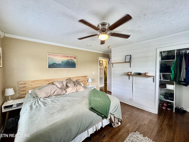 bedroom featuring wood finished floors, ornamental molding, baseboards, a textured ceiling, and ceiling fan