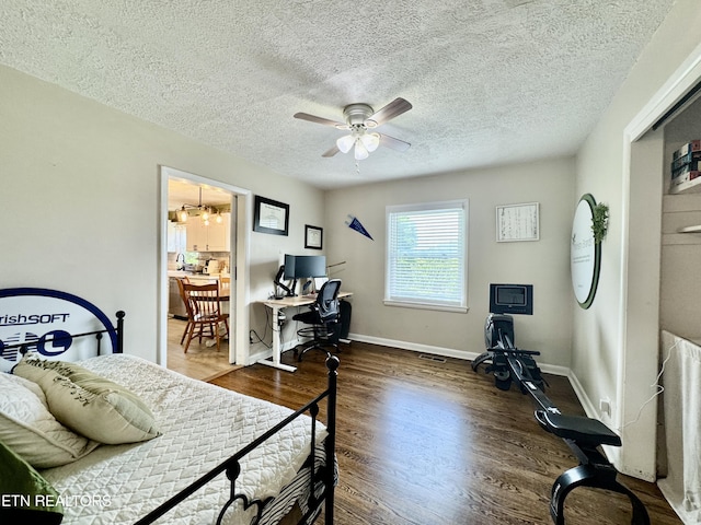 bedroom with a desk, wood finished floors, baseboards, a textured ceiling, and a ceiling fan