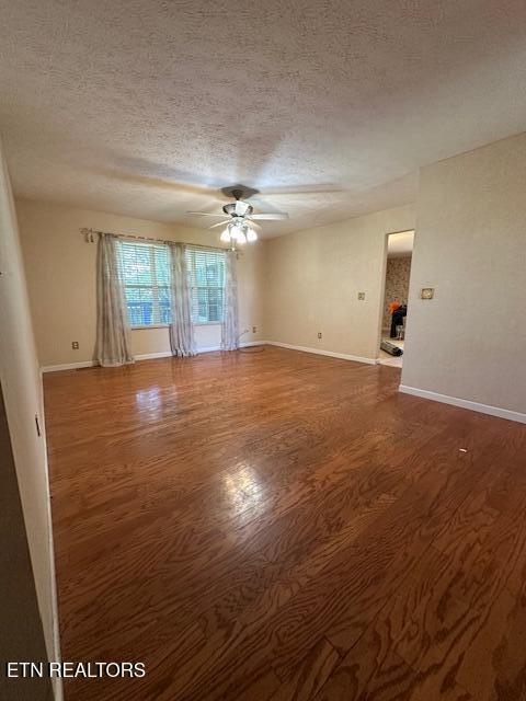 unfurnished room with wood finished floors, a textured ceiling, a ceiling fan, and baseboards