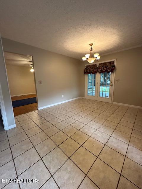 empty room featuring light tile patterned floors, a chandelier, baseboards, and a textured ceiling