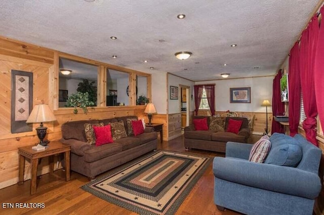 living room featuring wood walls, wood finished floors, and a textured ceiling