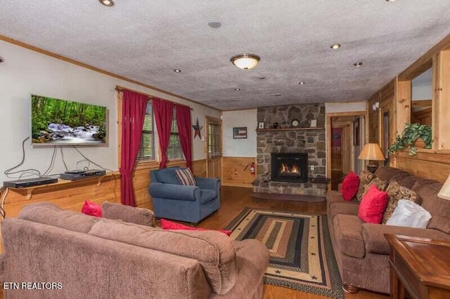 living room with wood finished floors, a fireplace, ornamental molding, and a textured ceiling