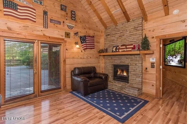 living area with wooden ceiling, wood finished floors, healthy amount of natural light, a stone fireplace, and beam ceiling