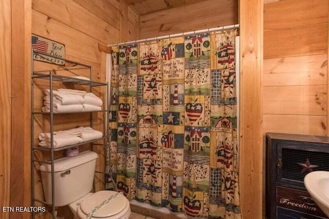 bathroom with wood walls, a shower with shower curtain, toilet, and a sink