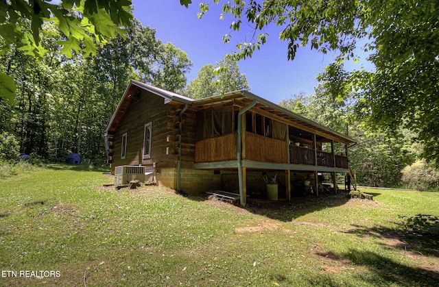 view of property exterior featuring a lawn, central AC, and log exterior