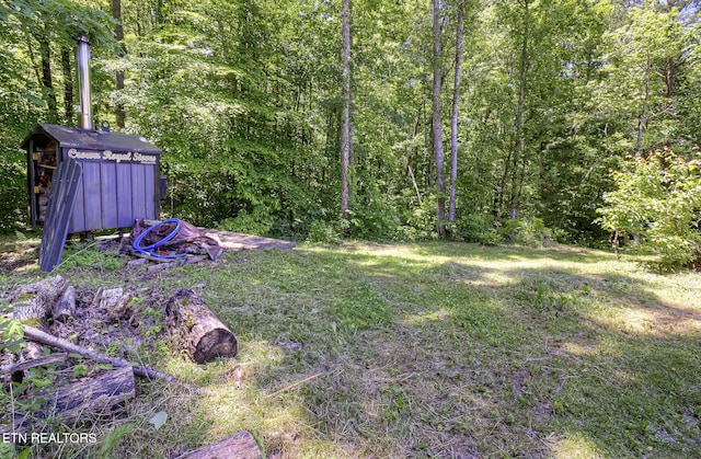 view of yard with a shed, an outbuilding, and a forest view