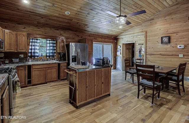kitchen with stainless steel appliances, wooden ceiling, a center island, wooden walls, and a sink