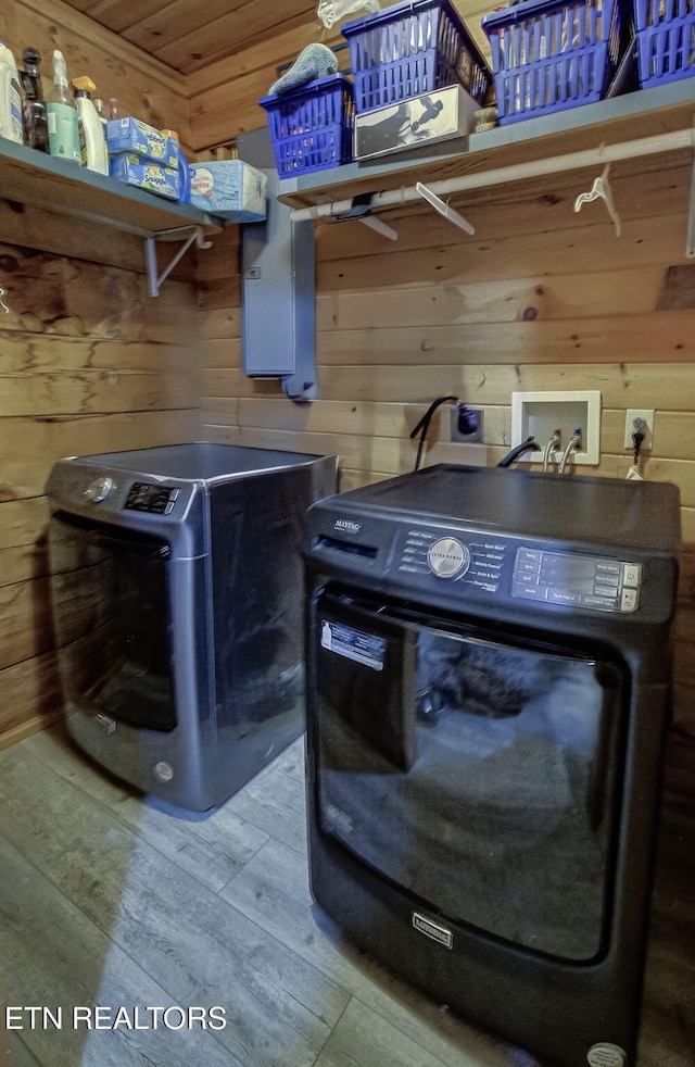 laundry room featuring independent washer and dryer, wood walls, and wood finished floors