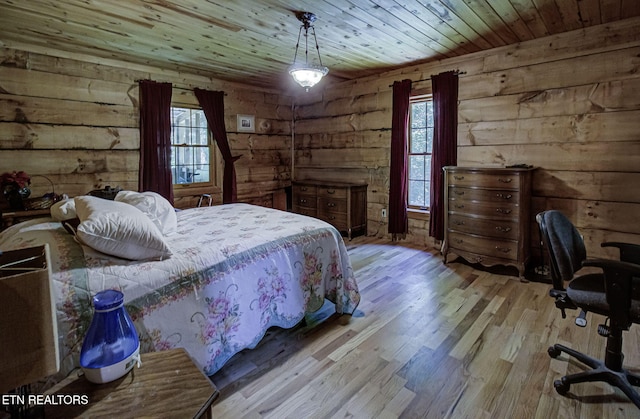 bedroom with wooden walls, wood ceiling, multiple windows, and wood finished floors