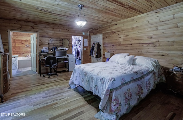 bedroom featuring wood finished floors, an office area, a spacious closet, wooden ceiling, and wood walls