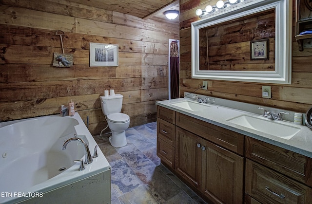bathroom with wooden walls, toilet, a tub with jets, and double vanity