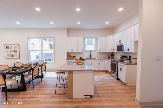 12516 Dalton View Ln, Knoxville, TN 37932 - kitchen featuring stainless steel electric stove, white cabinets, a kitchen breakfast bar, recessed lighting, and a kitchen island