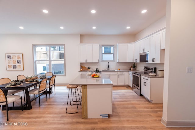 12516 Dalton View Ln, Knoxville, TN 37932 - kitchen featuring stainless steel range with electric stovetop, white cabinets, recessed lighting, a breakfast bar, and plenty of natural light