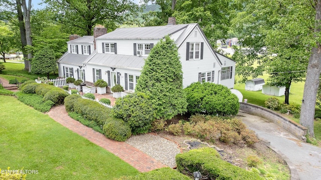 view of front facade with a chimney, metal roof, and a front yard