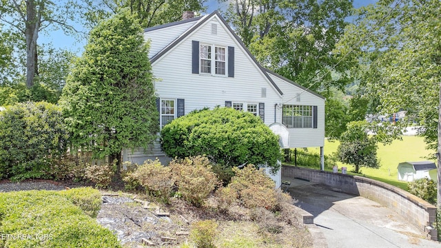 view of front of house with concrete driveway and a chimney