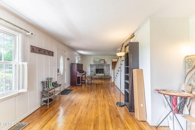 living room with light wood-type flooring, stairs, ornamental molding, a fireplace, and a decorative wall