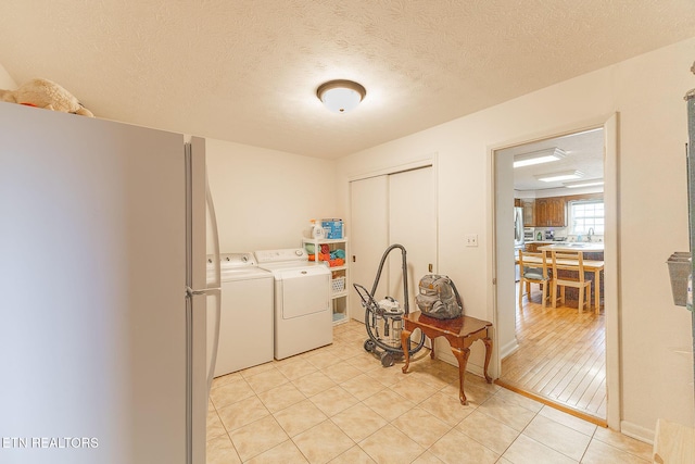 laundry area with washing machine and dryer, light tile patterned floors, and a textured ceiling