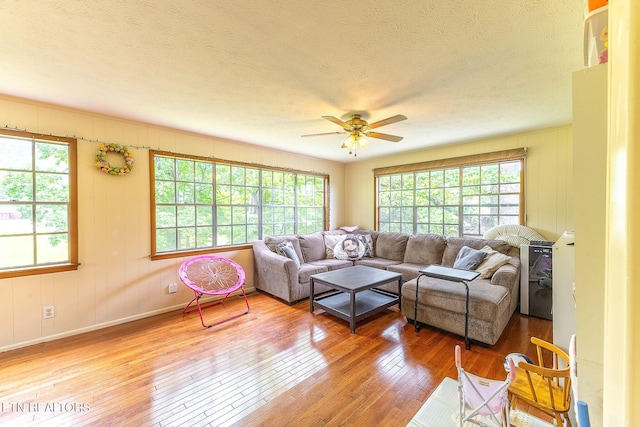 living room featuring plenty of natural light, wood-type flooring, ceiling fan, and a textured ceiling