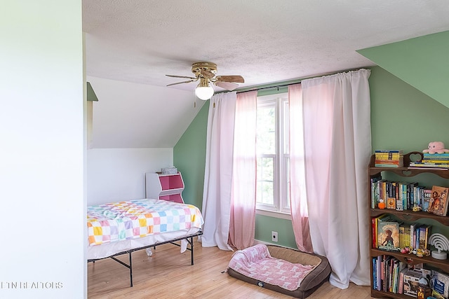 bedroom with wood finished floors, lofted ceiling, a textured ceiling, ceiling fan, and baseboards