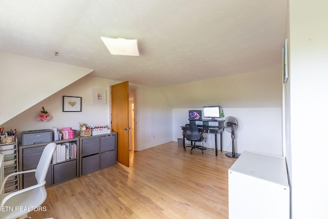 office space with light wood-style floors, baseboards, lofted ceiling, and a textured ceiling