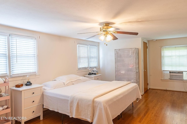 bedroom with cooling unit, multiple windows, and light wood-style flooring