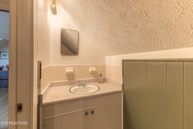 bathroom with vanity, a textured ceiling, and lofted ceiling